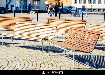 Simrishamn, Svezia - Aprile 1, 2016: alcune vuote panche di legno nella piazza della città e con le persone al di fuori della messa a fuoco in background. Foto Stock