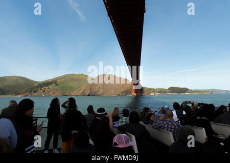 I passeggeri di un giro turistico in barca direttamente sotto il Golden Gate Bridge nella Baia di San Francisco, California, Stati Uniti d'America Foto Stock