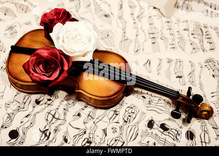 Vecchio violino le note musicali e tre rose Foto Stock