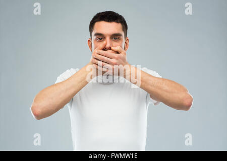 Uomo in bianco t-shirt che copre la bocca con le mani Foto Stock