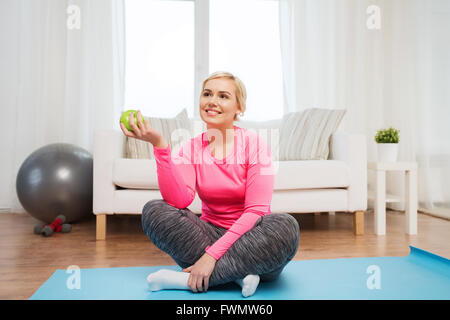 Donna felice di mangiare mela verde a casa Foto Stock