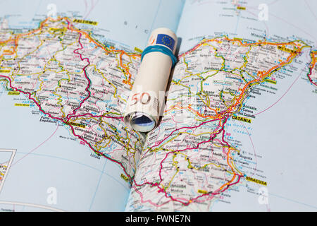 Le banconote in euro su una mappa geografica della Sicilia, Italia Foto Stock