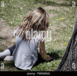 Prescott, Arizona, Stati Uniti d'America - 26 Marzo 2016: una ragazza non identificato con fiore a margherita seduti sul prato park Foto Stock