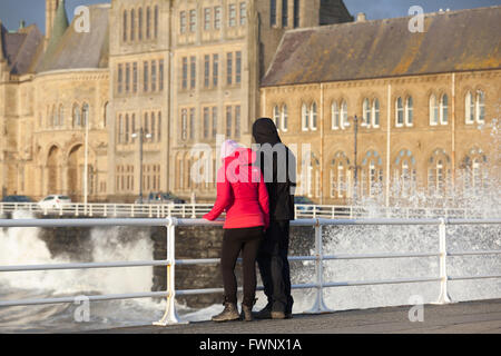 L uomo e la donna in piedi lungo la promenade guardando le onde splash contro le pareti Credito: Ian Jones/Alamy Live News Foto Stock