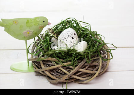 Bellissimo sfondo di pasqua con bird e nido con uova sul dipinto di bianco di tavole Foto Stock