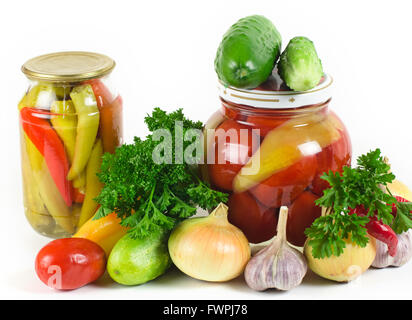 Cipolle, aglio cetrioli e pomodori e prezzemolo giacciono su di una superficie di luce. Una fila di due banche con le conserve di verdura Foto Stock