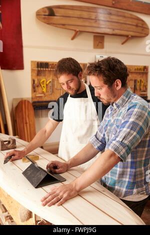 Carpentieri in tavola da surf officina con tavoletta digitale Foto Stock