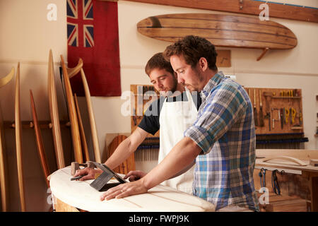 Carpentieri in tavola da surf officina con tavoletta digitale Foto Stock