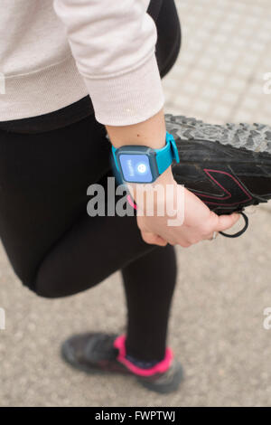 Giovane donna stretching dopo aver fatto un po' di esercizi e di indossare un orologio intelligente sul polso visualizzazione messaggio sani sul touch Foto Stock
