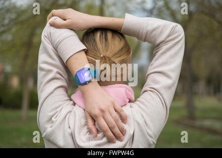 Giovane donna stretching dopo aver fatto un po' di esercizi e di indossare un orologio intelligente sul polso visualizzazione messaggio sani sul touch Foto Stock