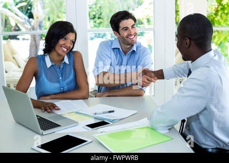 Coppia felice stringono le mani con agente immobiliare Foto Stock