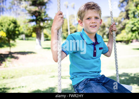 Ragazzo seduto su un altalena nel parco Foto Stock