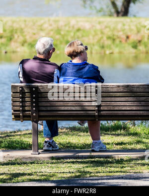 Una coppia senior a sedersi su una panca in legno in compagnia guardando a nord del fiume canadese e lago Overholser. Oklahoma City, Oklahoma, Stati Uniti d'America. Foto Stock