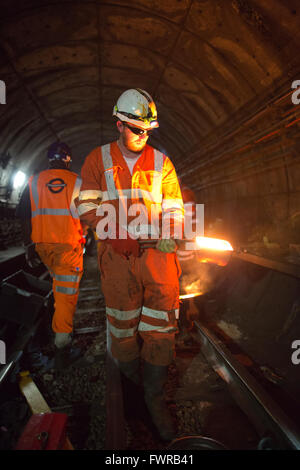 Saldare gli ingegneri di pista di sostituzione componenti insieme utilizzando thermite saldatura sulla metropolitana di Londra binario, London, Regno Unito Foto Stock