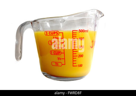 Una misura di Pyrex brocca piena di orange liquido colorato fotografati contro uno sfondo bianco. Foto Stock