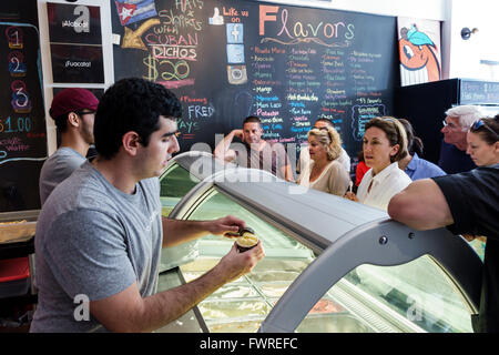 Miami Florida,Little Havana,Calle Ocho,adulto ispanico,adulti,uomo uomo maschio,Azucar Ice Cream Company,interno,banco,clienti,linea,coda,servin Foto Stock