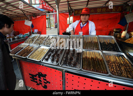 Spiedini di ragni e scorpioni, larva e altri insetti bizzarro venduti in uno stallo presso la strada vivace mercato alimentare a Wang Fu Jing. Foto Stock