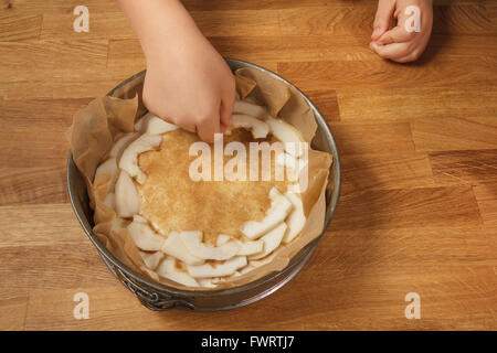 Mette mano fette di Apple su una fetta di torta di mele prima della cottura Foto Stock