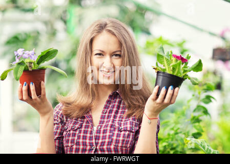 Donna sorridente in serra con vasi di fiori Foto Stock