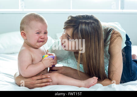 Donna con figlio di pianto sul letto di casa Foto Stock