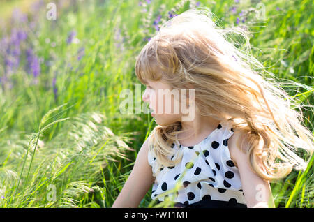 Bella ragazza bionda in verde prato con fiori Foto Stock
