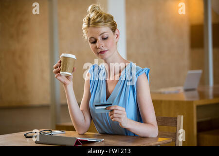 Bella donna avente caffè mentre lo shopping online Foto Stock