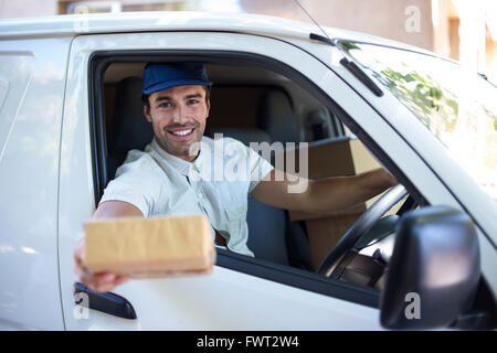 Consegna sorridente uomo dando una scatola di cartone Foto Stock