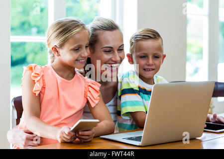 Sorridente madre e bambini guardando al laptop Foto Stock