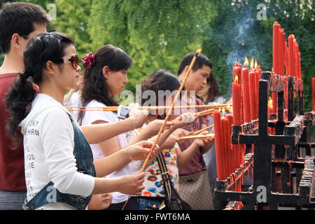 Donna accendendo candele come parte di una cerimonia buddista al Giant Pagoda dell'Oca Selvaggia, Xian, Cina. Foto Stock