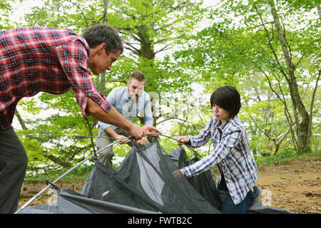 Multi-etnico gruppo di amici mettendo su una tenda in un campeggio Foto Stock