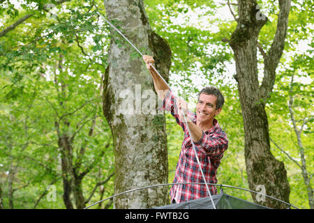 Uomo caucasico mettendo su una tenda in un campeggio Foto Stock