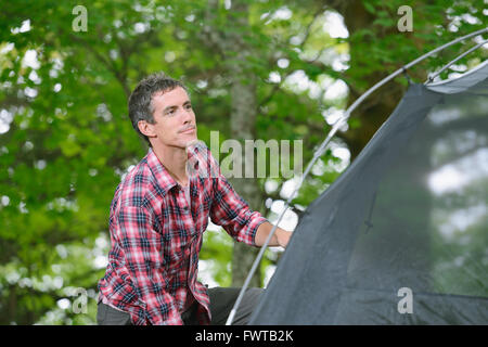 Uomo caucasico mettendo su una tenda in un campeggio Foto Stock