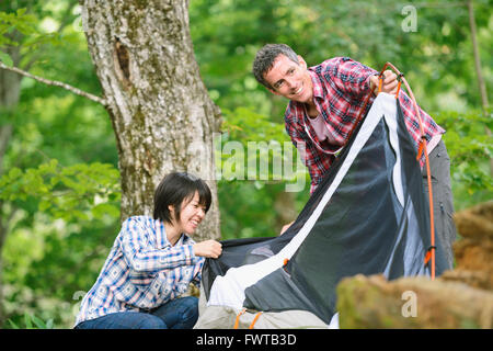 Gli amici mettendo su una tenda in un campeggio Foto Stock