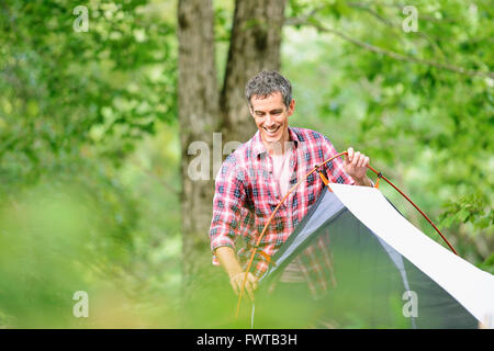 Uomo caucasico mettendo su una tenda in un campeggio Foto Stock