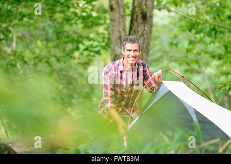 Uomo caucasico mettendo su una tenda in un campeggio Foto Stock