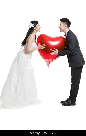 Felice sposa e lo sposo tenendo un cuore palloncino a forma di Foto Stock