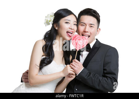 Felice sposa e lo sposo tenendo un a forma di cuore lecca-lecca Foto Stock