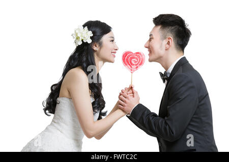 Felice sposa e lo sposo tenendo un a forma di cuore lecca-lecca Foto Stock