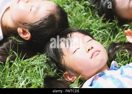 I ragazzi giapponesi che posa in erba in un parco della città Foto Stock