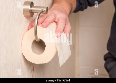Una mano protesa alla carta igienica rotolo durante una visita Foto Stock