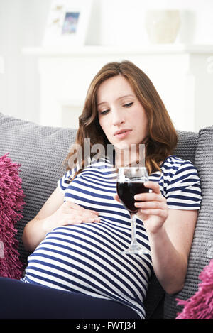 In questione donna incinta di bere vino rosso Foto Stock