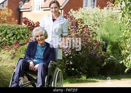 Ritratto del caregiver spingendo Senior donna in sedia a rotelle Foto Stock