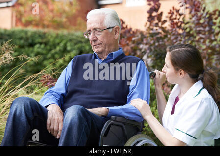 L'infermiera consolante Senior uomo in sedia a rotelle Foto Stock
