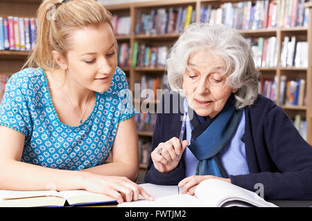 Senior donna che lavorano con insegnante in libreria Foto Stock