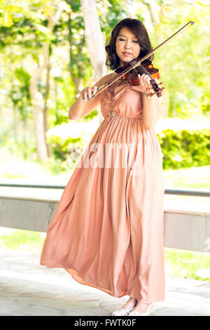 Giovane donna suona il violino in giardino Foto Stock