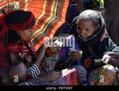 Donne Oromo sotto l'ombrello coloratissimo mercato settimanale bati, Etiopia. Foto Stock