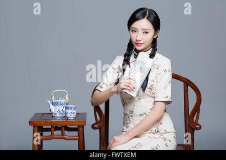 Giovane bella donna in cheongsam tradizionale con un libro Foto Stock