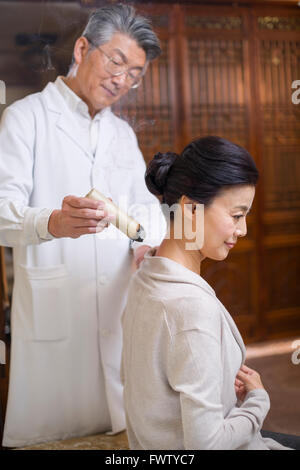 Senior medico cinese dando moxibustione Foto Stock