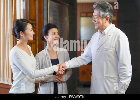 Senior medico cinesi stringono le mani con paziente Foto Stock