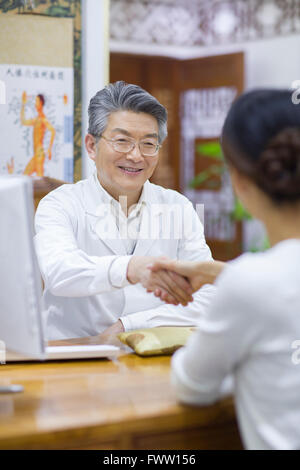 Senior medico cinesi stringono le mani con paziente Foto Stock